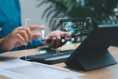 Personne utilisant une tablette et un clavier devant des interfaces graphiques de cybersécurité affichées en surimpression, avec des icônes de connexion sécurisée, de protection des données, de cloud et d’intelligence artificielle. L’image illustre la sécurité numérique, la gestion des données et les technologies informatiques.