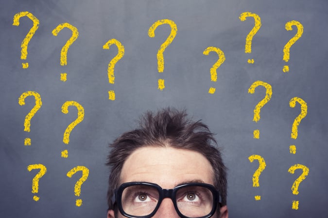 Personne avec des lunettes sous plusieurs points d’interrogation jaunes sur fond sombre.