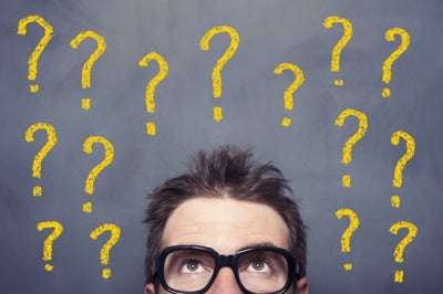 Personne avec des lunettes sous plusieurs points d’interrogation jaunes sur fond sombre.