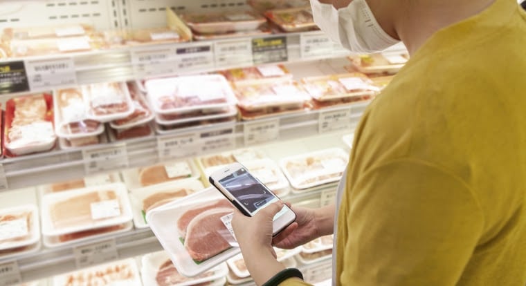 homme avec masque scan avec son smartphone une étiquette de barquette de viande