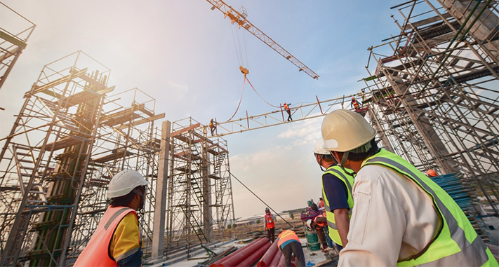 hommes en tenues de travail devant un chantier de construction