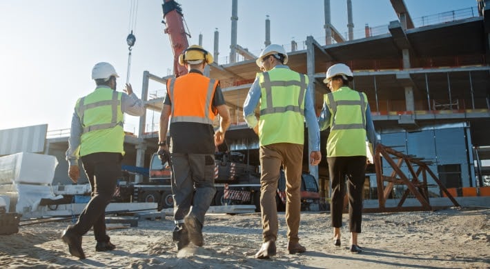 hommes et femmes de dos avec équipement de sécurité sur un chantier de construction