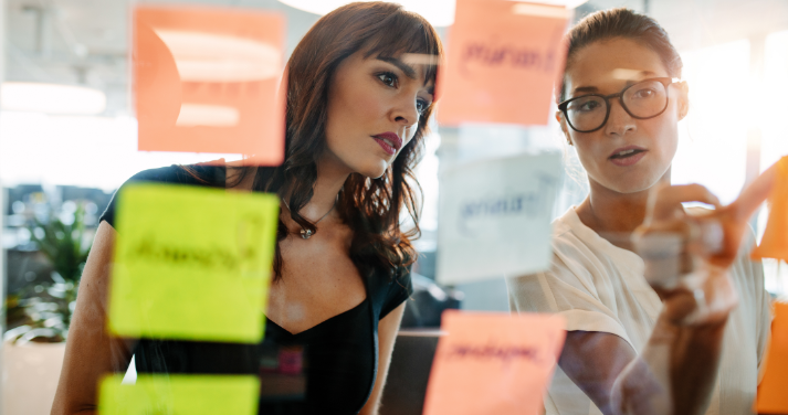 deux femmes discutent devant un tableau vitré