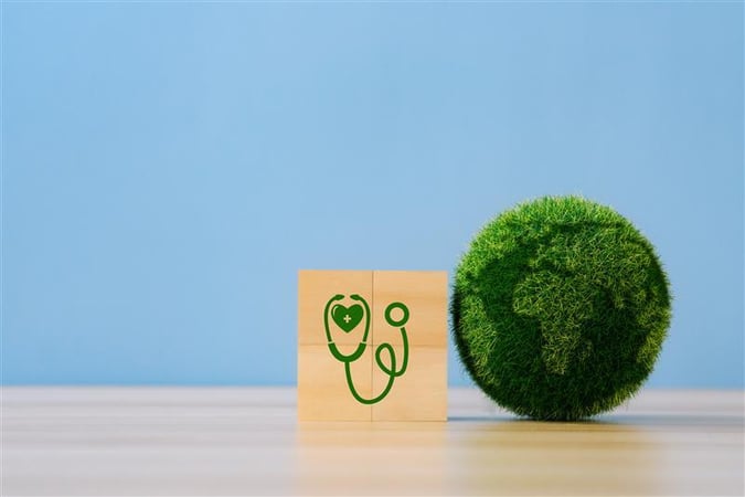 Bloc en bois avec un stéthoscope dessiné à côté d’un globe vert végétal, sur fond bleu.