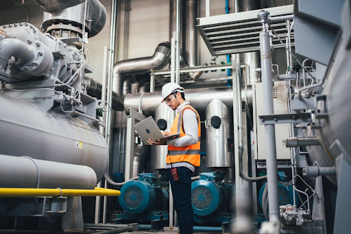 homme en tenu de travail avec un ordinateur portable dans un environnement industriel